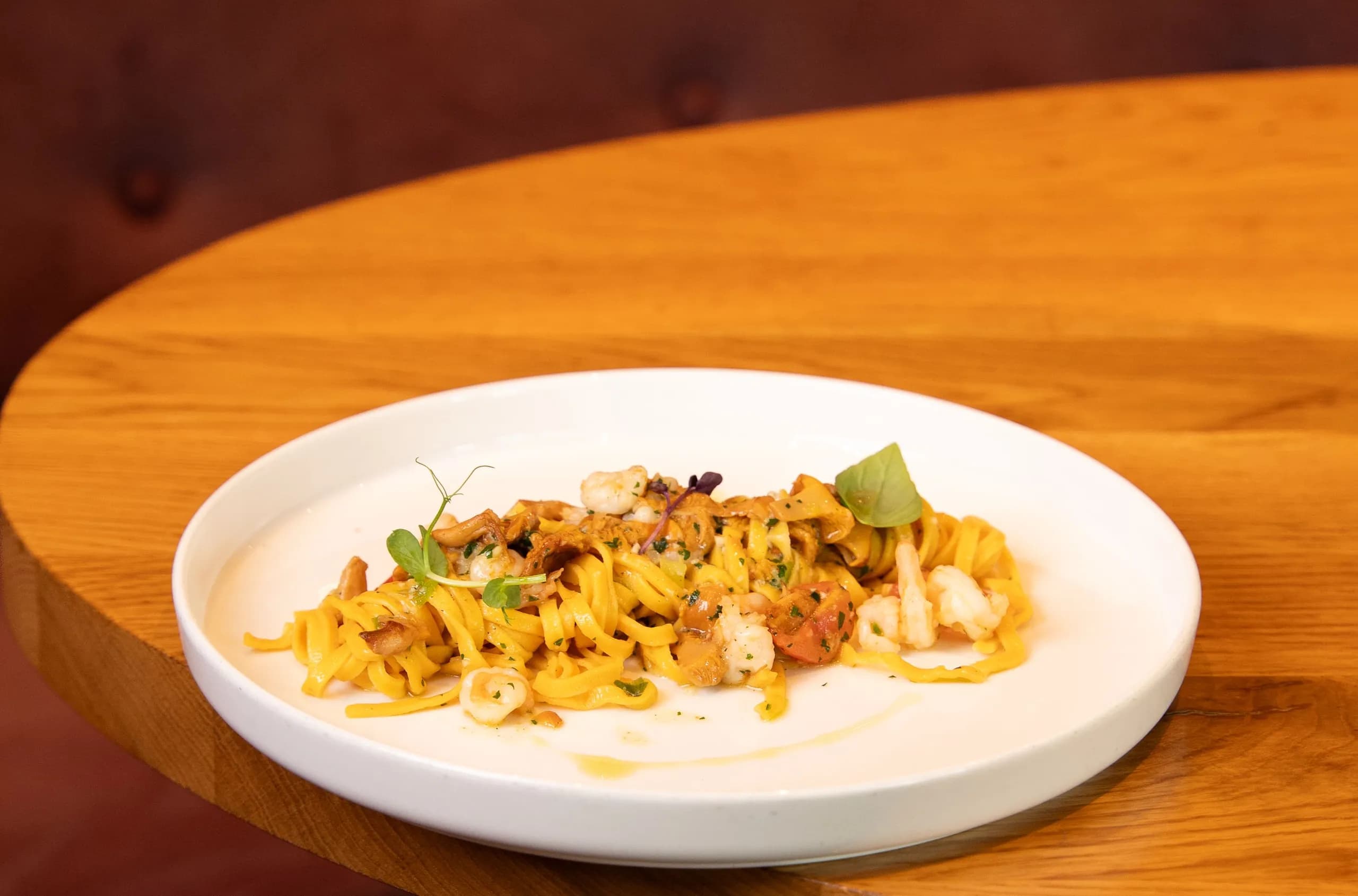 Ein Teller Pasta mit Garnelen auf dem Holztisch im Gastraum